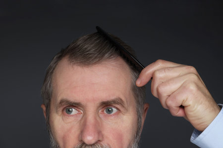 Man combing his hair on dark grey background, closeupの写真素材