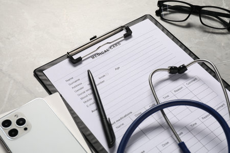 Composition with medical card form and pen on gray background, closeup