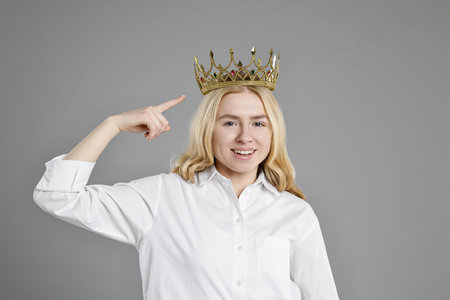 Happy woman pointing at elegant crown on grey backgroundの写真素材