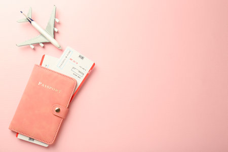 Passport with tickets and plane model on pink background, flat lay. Space for textの写真素材