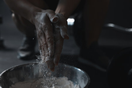 Woman applying talcum powder onto her hands above bowl before training in gym, closeupの写真素材