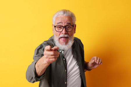 Emotional senior man with beard on yellow background