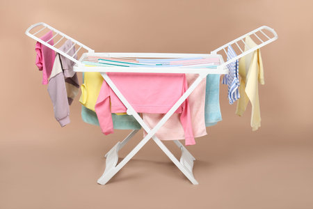 Drying rack with fresh clean laundry on beige background