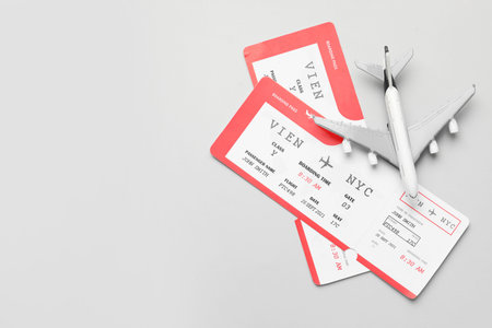 Travel agency. Flight tickets and plane model on grey background, flat lay. Space for text