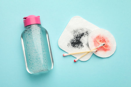 Dirty cotton pads, swabs and micellar water on light blue background, top viewの写真素材