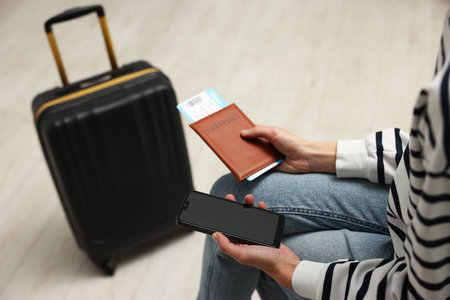 Traveller with passport, flight ticket and smartphone indoors, closeupの写真素材