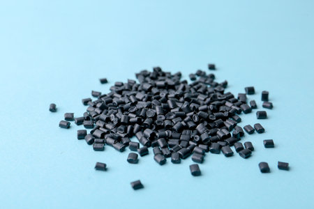 Pile of black plastic granules on light blue background, closeupの写真素材