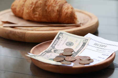 Tip, receipt and croissant on wooden table, closeupの写真素材