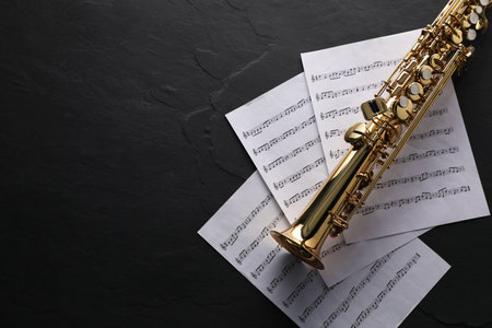 Saxophone and music notes on black table, top view.の写真素材