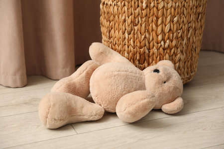 Teddy bear near basket on floor at homeの写真素材