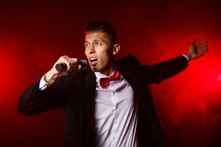 Talented singer performing on red background with smokeの写真素材