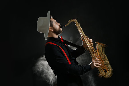Professional musician playing saxophone on black background with smokeの写真素材
