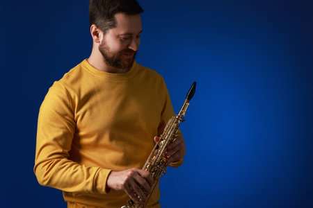 Professional musician with soprano saxophone on blue background. Space for textの写真素材
