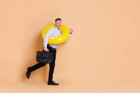 Businessman with inflatable ring and briefcase on beige background, space for textの写真素材