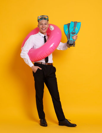 Businessman with inflatable ring, flippers and diving mask on orange backgroundの写真素材