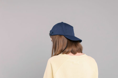 Woman in stylish baseball cap on grey background, back view. Mockup for design