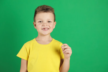 Cute little boy with missing tooth on green background, space for text. Waiting for tooth fairyの写真素材