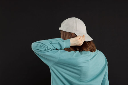 Woman in stylish baseball cap on black background, back view. Mockup for designの写真素材