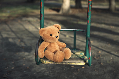 Brown teddy bear on swing outdoorsの写真素材