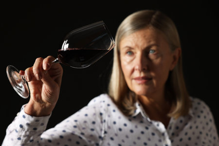 Professional sommelier analyzing quality of red wine on black background, selective focusの写真素材
