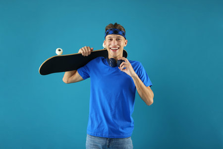 Happy man with skateboard on light blue backgroundの写真素材