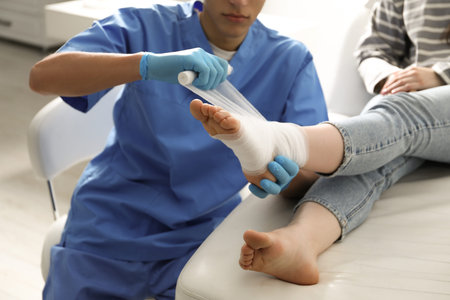 Doctor bandaging patient's foot in clinic, closeupの写真素材