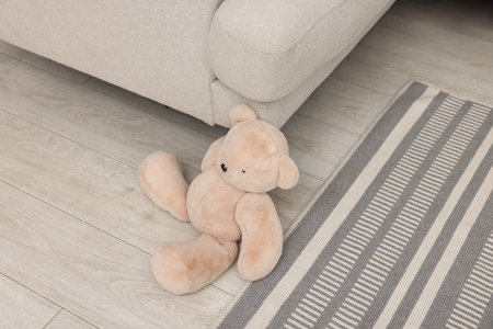 Teddy bear near sofa on floor in roomの写真素材