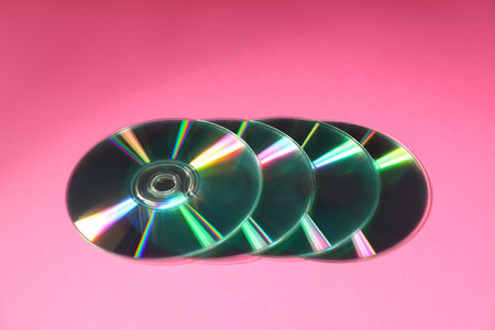 Many shiny compact discs on pink background, closeupの写真素材