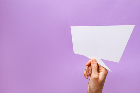 Person holding blank speech bubble on lilac background, closeup. Space for textの写真素材