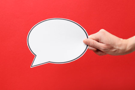 Woman holding blank speech bubble on red background, closeup. Space for text