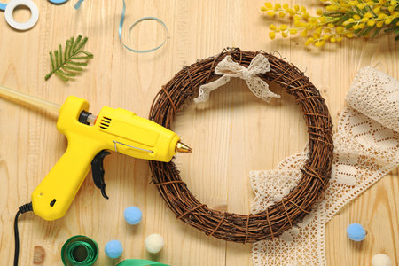 Hot glue gun and handicraft materials on wooden background, flat layの写真素材
