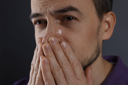 Man crying on grey background, closeup