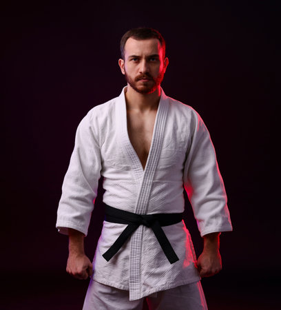 Karate fighter wearing uniform in color light against black backgroundの写真素材