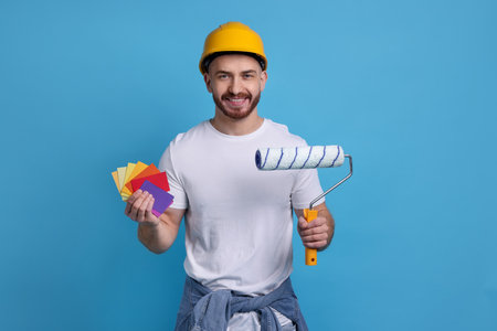 Man wearing hardhat with roller and color samples on blue backgroundの写真素材