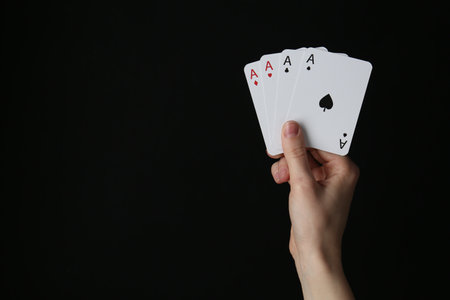 Woman with playing cards against black background, closeup.の写真素材