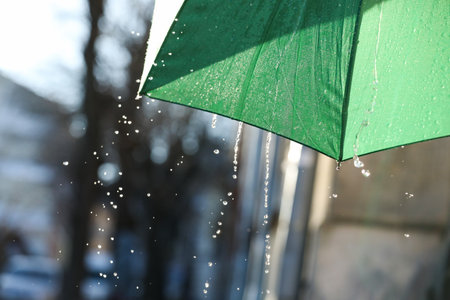 Open green umbrella under pouring rain outdoors, closeupの写真素材