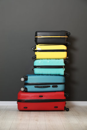 Stack of colorful suitcases on floor near black wall