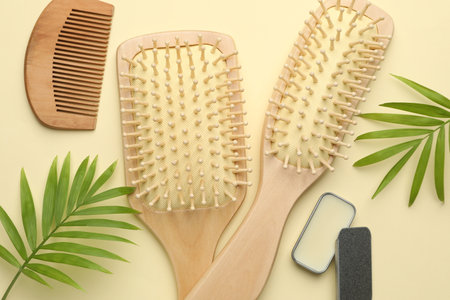 Wooden hair brushes, comb, and green leaves on beige background, flat layの写真素材