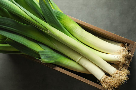 Fresh raw leeks in wooden crate on grey table, top viewの写真素材