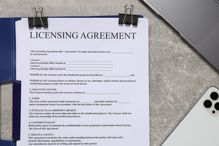 Licensing agreement document, laptop and smartphone on gray textured table, flat layの写真素材