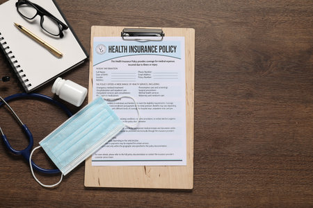 Flat lay composition with health insurance policy form on wooden table, space for textの写真素材