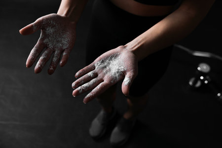 Woman with powder on her hands before training against black background, closeupの写真素材