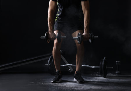 Man training with barbells against black background, closeupの写真素材