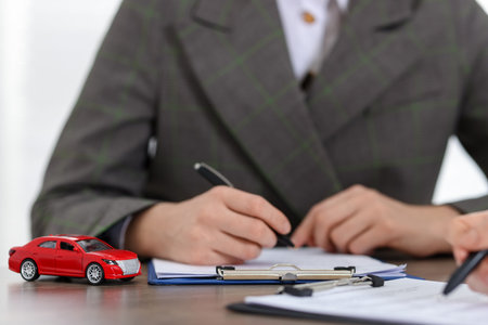 Manager and client signing car purchase agreement at wooden table, selective focus. Buying autoの写真素材