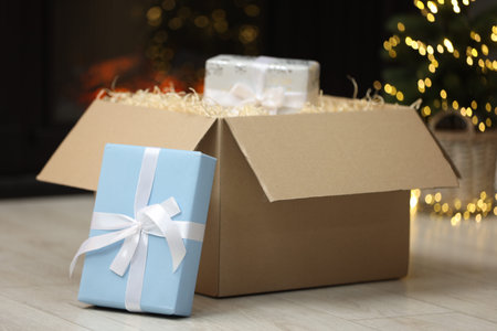Parcel with gift boxes on floor in room decorated for Christmas. Bokeh effect