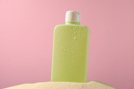 Bottle of sun protection product on sand against pink backgroundの写真素材