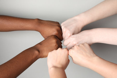 Stop racism. People of different skin colors bumping fists on light grey background, closeupの写真素材
