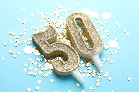 50th birthday. Number shaped candles and confetti on light blue background, closeupの写真素材