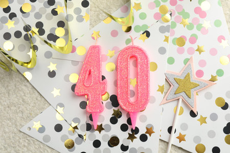 40th birthday. Number shaped candles, party decor and confetti on light textured background, flat layの写真素材