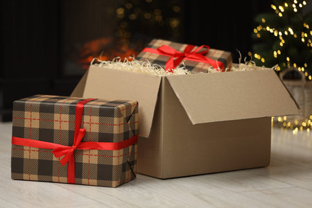 Parcel with gift boxes on floor in room decorated for Christmas. Bokeh effect